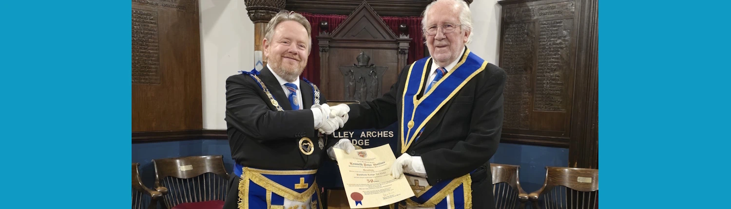 Peter Hollins 50 years a Freemason receiving an illuminated scroll from the APGM, David McGurty